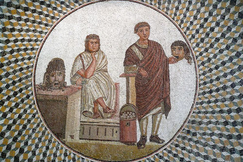 Mosaico dalla Casa delle Maschere. Scena teatrale, un poeta seduto e un attore che regge una maschera comica. Metà del III secolo d.C. Musée archéologique de Sousse. Fonte: https://studiahumanitatispaideia.wordpress.com/tag/patrios-politeia/